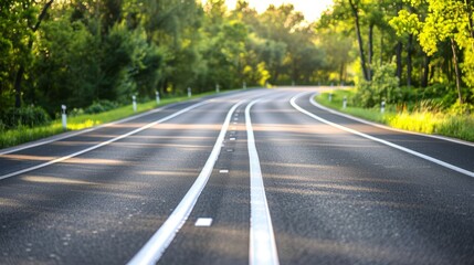 Obraz premium An empty road, flanked by trees on either side, features a white line demarcation down its center