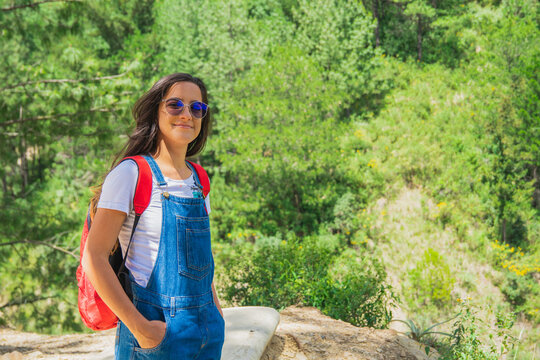 young traveler looking happily ahead, enjoying her trip and hike in the mountains.
