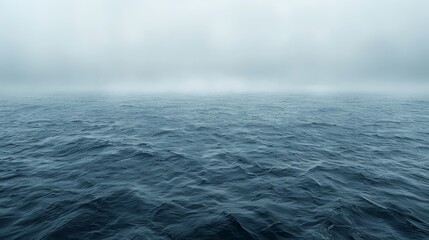   A large body of water, heavily shrouded in thick fog and lightly rippled with small waves