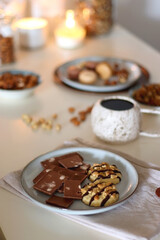Cup of tea or coffee, cookies, macaroons, chocolate, various nuts and cocoa powder on white background. Selective focus.