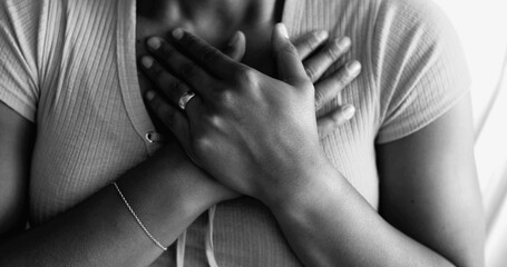 Hopeful Young African American Woman with Hands on Chest, Expressing Gratitude and Faith, Gesturing Heartfelt Symbol of Thankfulness in black and white
