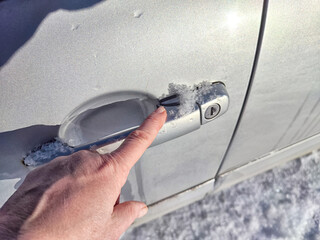 Frozen Car Lock on a Cold Winter Day. Woman person attempts to unlock a frozen car door, showing...