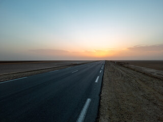 Beautiful colourful sunset over endless empty road in middle of desert. Asphalt highway in Tunisia,...