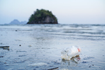 Waves from the sea are splashing plastic pet bottle left on the beach, Plastic waste pollution or...