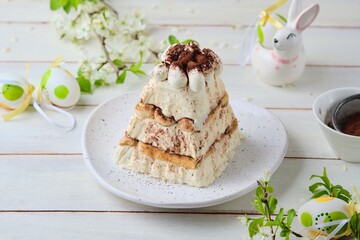 Dessert, cottage cheese Easter in the style of tiramisu with cottage cheese cream and cookies on a ceramic plate on a light concrete background. World holidays, Christianity