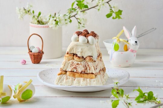 Dessert, cottage cheese Easter in the style of tiramisu with cottage cheese cream and cookies on a ceramic plate on a light concrete background. World holidays, Christianity