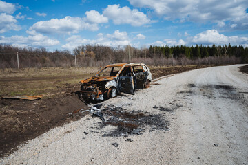 A car burned to the ground stands on the side of the road outside the city, an accident that killed...
