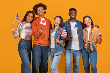 Multiracial friends holding international flags on orange background