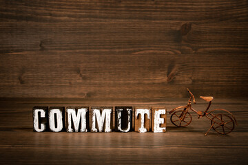COMMUTE. Text from alphabet blocks and rusty miniature bicycle on wood texture background - 792001478
