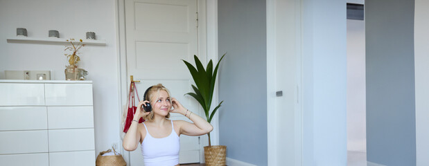 Vertical shot of smiling young woman using video tutorials for workout at home, sitting with laptop...