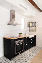 Vertical shot black kitchen island with drawers stove and convection cooker and modern appliances in scandinavian style apartment in new building. Copyspace