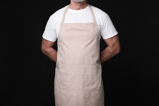 Man wearing kitchen apron on black background, closeup. Mockup for design