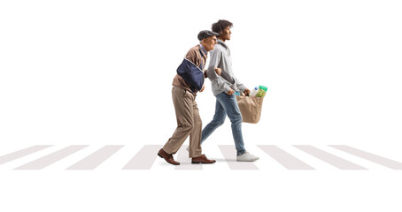 Young african american man helping a senior with an injury and carrying grocery bags at a pedestrian crossing