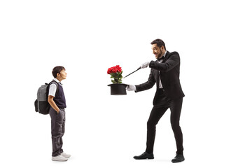 Boy watching a magician performing a trick with hat and red roses