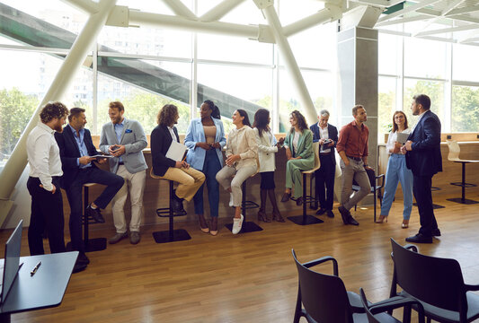 Group of diverse multinational business people men and women chatting after a meeting. Company employees or group of staff talking with each other in the office during the break in meeting room.