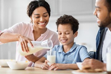 Parent pouring milk at breakfast with family
