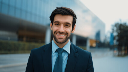 Portrait of smiling business man looking at camera while standing at building. Closeup of...