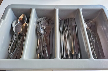 clean cutlery in a cutlery box with knives, forks, spoons in a canteen.