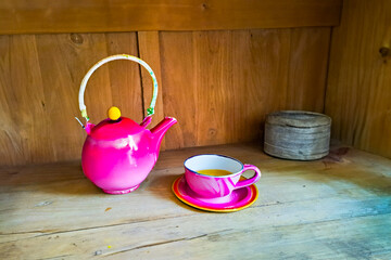 ceramic cup and kettle of tea, coffe with a pink floral motif, wooden background