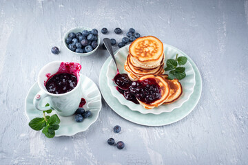 Traditional American pancakes with blueberry fruits and jam served as close-up on a Nordic design plate