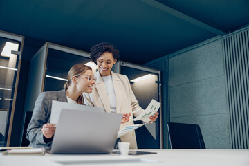 Smiling female boss discussing project with employee showing presentation to team leader