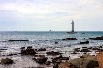 View of the lighthouse in the sea near the rocky shore. Heavenly Grottoes Park, Sanya, China