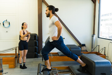 Pilates instructor coaching student on reformer bed