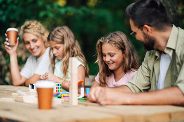 Fun family is playing wooden block game in nature.