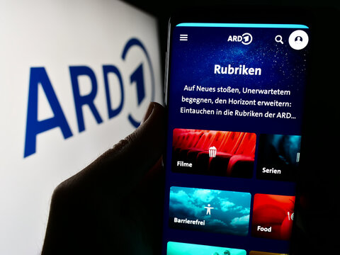 Stuttgart, Germany - 04-10-2024: Person holding cellphone with webpage of German public-service broadcasting organisation ARD in front of logo. Focus on center of phone display.