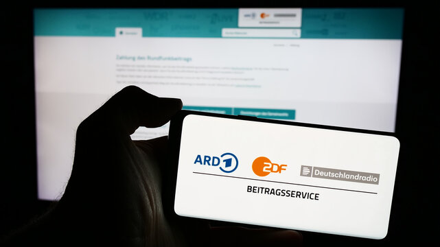 Stuttgart, Germany - 04-10-2024: Person holding mobile phone with logo of ARD ZDF Deutschlandradio Beitragsservice in front of web page. Focus on phone display.