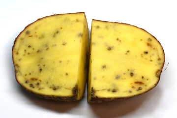 a cut of a potato tuber with black spots and streaks. The texture of a diseased potato tuber. Unsuitable for use in food and for planting. Selective focus. Dirty background