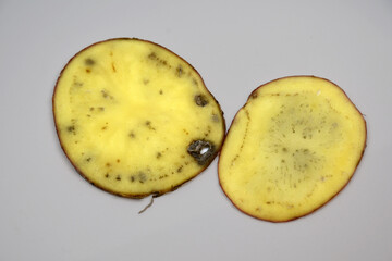 a cut of a potato tuber with black spots and streaks. The texture of a diseased potato tuber....