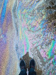 Colorful oil stains on asphalt in parking lot - standing in front point of view