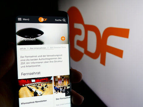 Stuttgart, Germany - 04-10-2024: Person holding cellphone with web page of television broadcaster Zweites Deutsches Fernsehen (ZDF) with logo. Focus on center of phone display.
