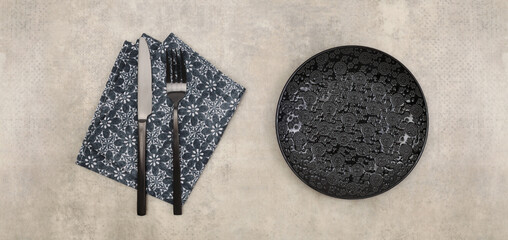 Empty black gray plate, fork; knife, napkin on marble rustic concrete background. Top view, flat lay.