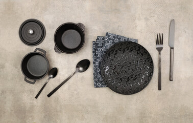 Empty black gray plate, fork; knife, spoon, napkin on marble rustic concrete background. Top view, flat lay.