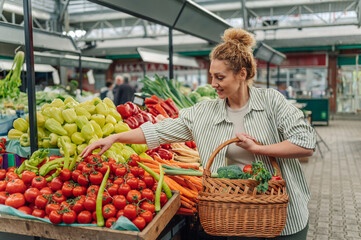 Woman with basket buying organic vegetables at farmer's market.