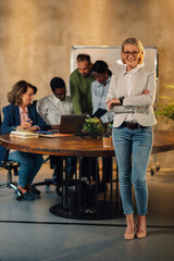 Confident senior businesswoman standing at office during the meeting.