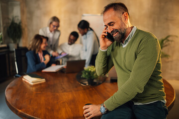 Mature boss having phone call with business partners during meeting.