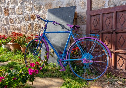 Buntes farbenfrohes Fahrrad an einem Haus mit Garten und Blumen am Mittelmeer, in der Sonne