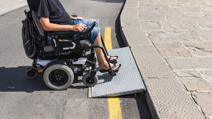 Male tourist on wheelchair crossing over the threshold ramp on the seaside promenade. Disability...