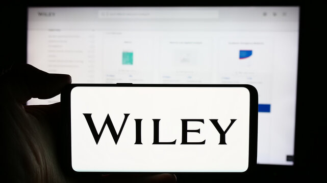 Stuttgart, Germany - 04-12-2024: Person holding cellphone with logo of US publishing company John Wiley and Sons Inc. in front of business webpage. Focus on phone display.