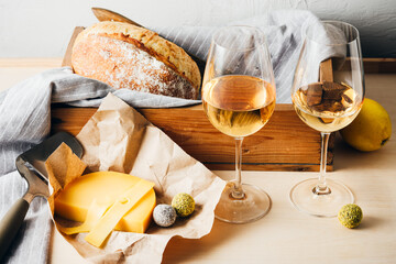 White wine, cheese, bread on the table.