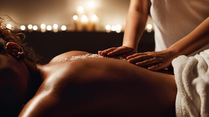 Obraz premium African-american woman enjoying salt scrub massage at spa