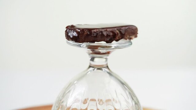 Melting of chocolate bar on transparent dish against white background