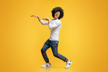 Funny black guy dancing in egypt style on orange background