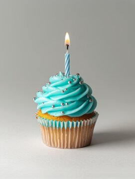 Blue frosted cupcake with a lit birthday candle - A simplistic yet captivating image of a cupcake with blue icing and a single burning candle