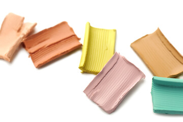 Samples of different color correcting concealers on white background, closeup