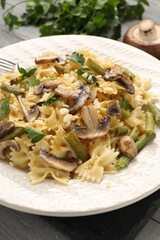Vegetarian pasta with mushrooms, parsley, string beans and cheese on grey wooden table, closeup