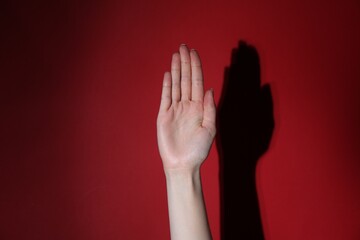 Woman showing open palm on red background, closeup